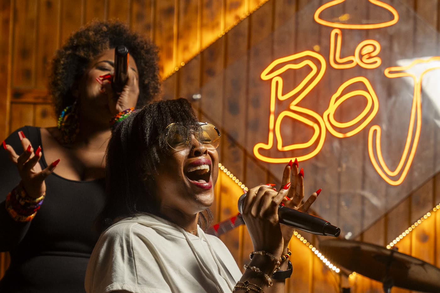 Deux chanteuses au micro devant l'enseigne néon du Boj