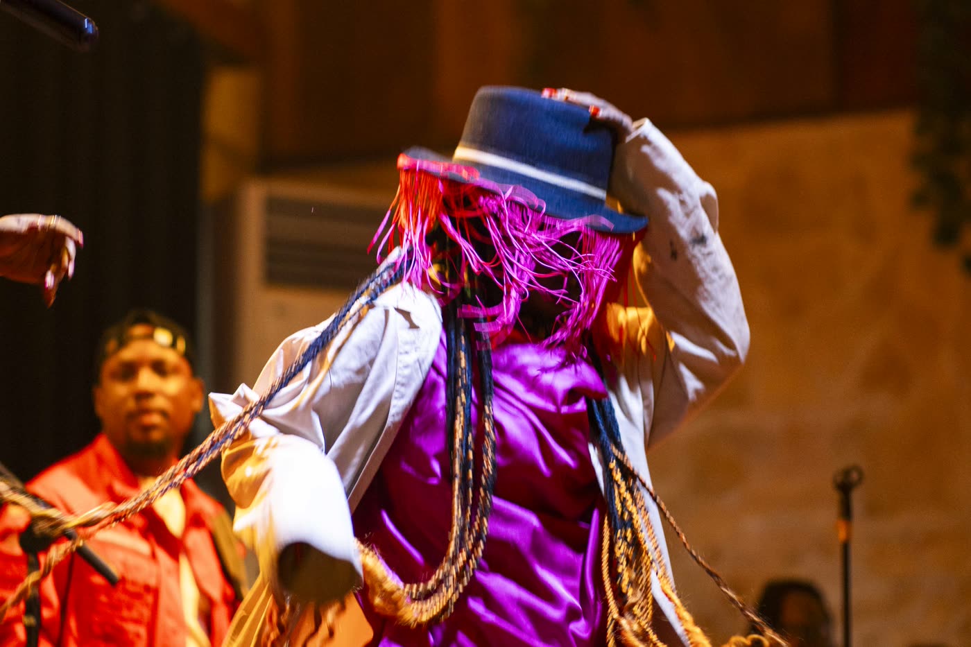 Danseuse en costume de scène, chapeau et tresses colorées, en plein show au Boj